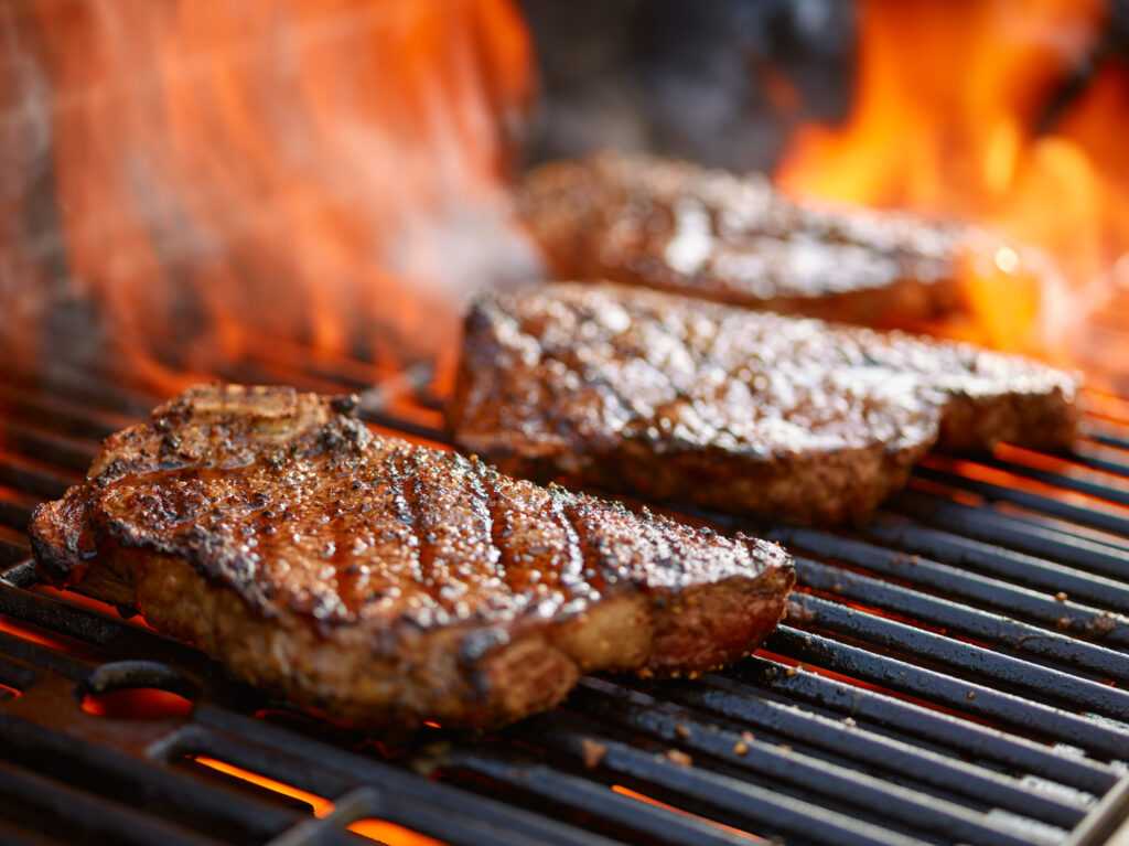 Grilling steaks on a flaming grill 